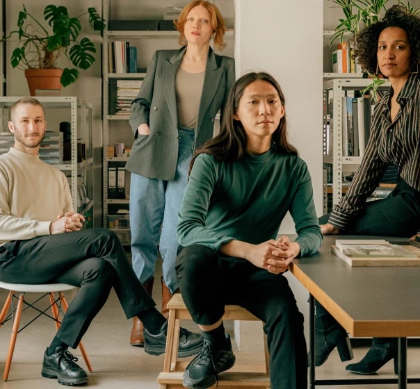 Four colleagues gathered in a bookshelf lined office